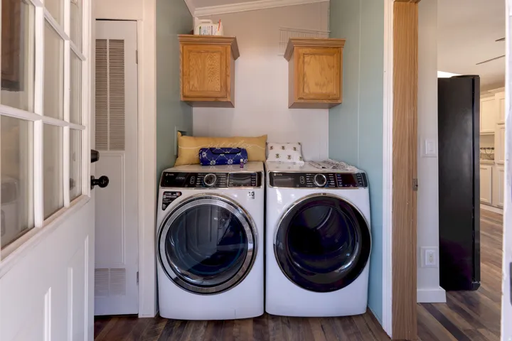 Laundry area featuring wood-finish flooring and two overhead wood cabinets