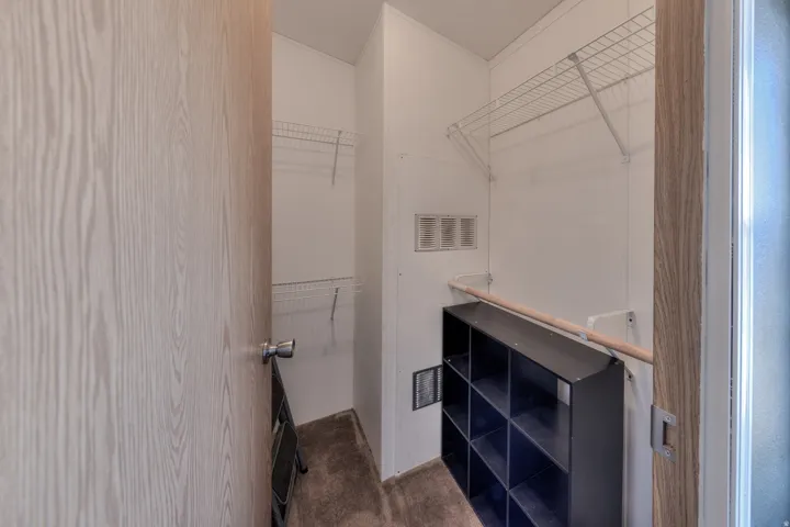 Walk-in closet featuring built-in wire shelving, a wooden clothing rod, and a modular storage unit