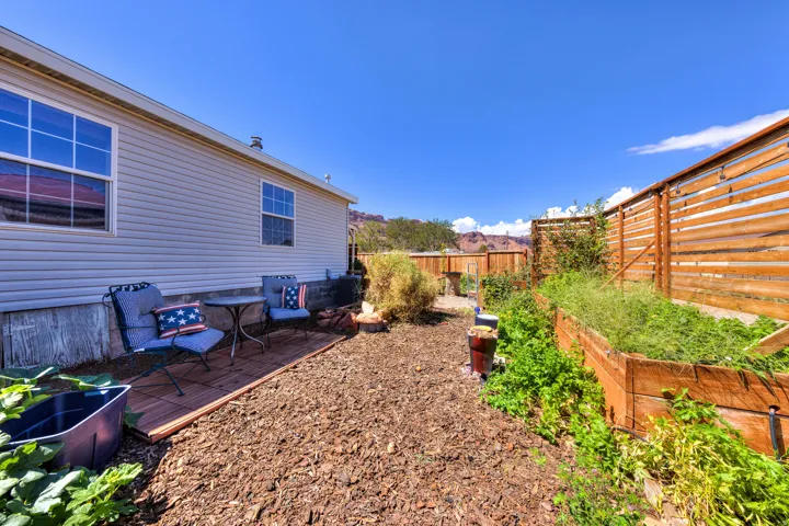 Exterior siding, wood privacy fencing, raised garden beds, and wood-finish patio decking