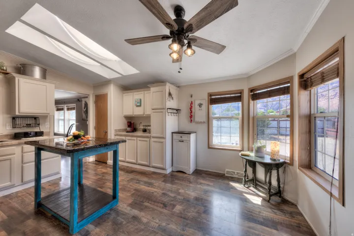 Wood-finish flooring, recessed lighting, ceiling fan, and multiple windows