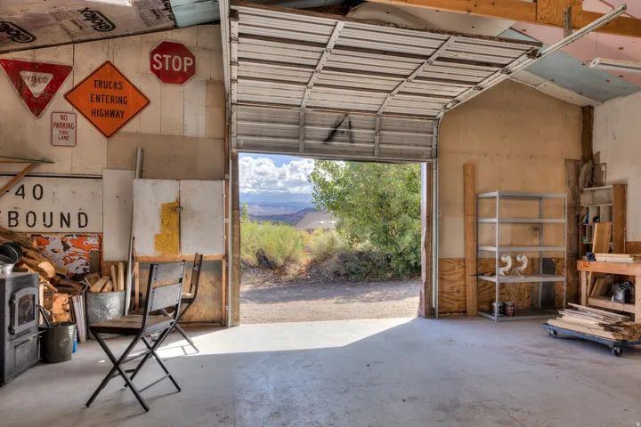 Spacious garage with concrete flooring, open roll-up door, and exposed wood ceiling joists