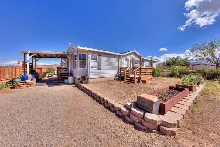 Gravel driveway leading to a covered patio with a wood privacy fence