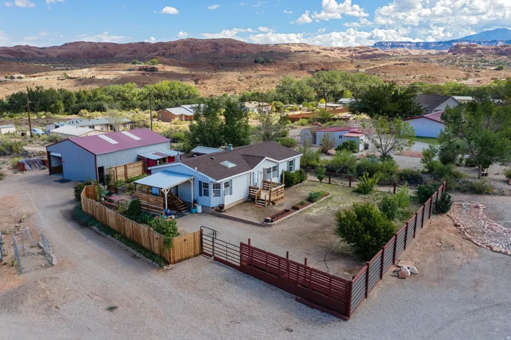 Single-story residence with a covered porch, fenced perimeter, metal workshop, and gravel driveway