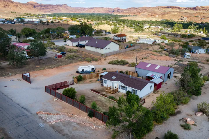 Expansive property featuring a detached workshop structure with a metal roof, a fenced perimeter, and a gravel driveway