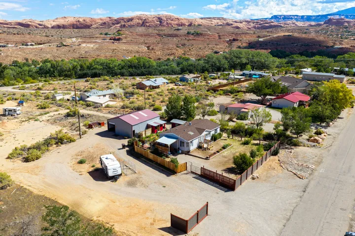 Single-story residence with a fenced front yard, gravel driveway, and detached metal-sided outbuilding