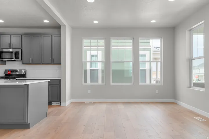 Open-concept living area featuring wood-finish flooring, recessed lighting, and multiple windows