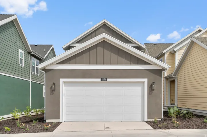 Attached garage featuring a white door, exterior wall sconces, and a stucco finish