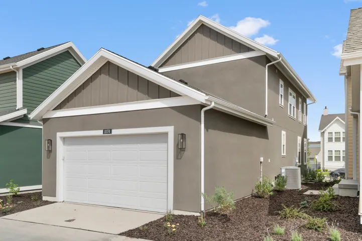 Contemporary exterior featuring stucco and vertical siding accents, an attached garage, and an air conditioning unit