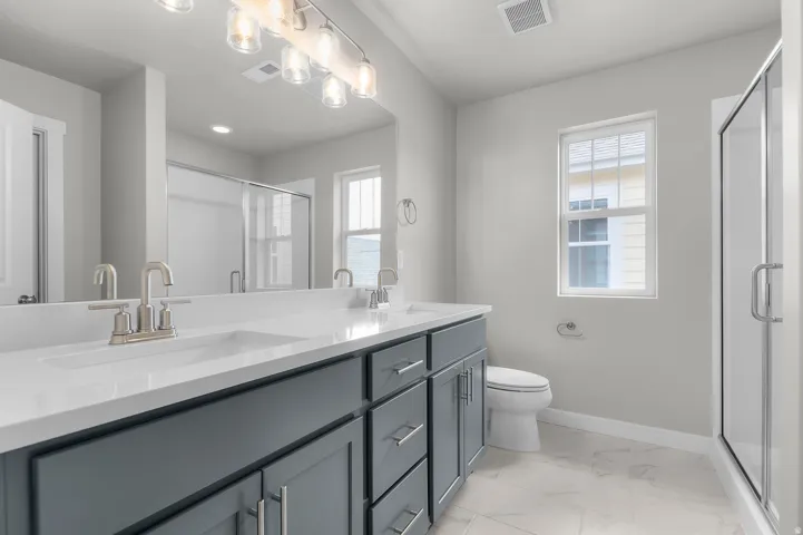 Dual vanity with gray cabinetry, white countertops, and brushed nickel fixtures