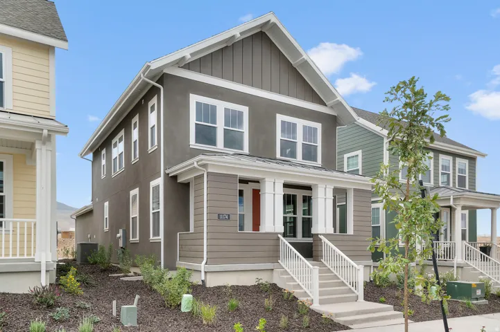 Two-story residence featuring a covered front porch, an exterior combining siding and stucco finishes, and a gabled roofline