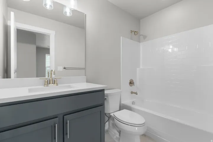 Vanity with white countertop and integrated sink, brushed nickel faucet, large mirror, and three-light fixture