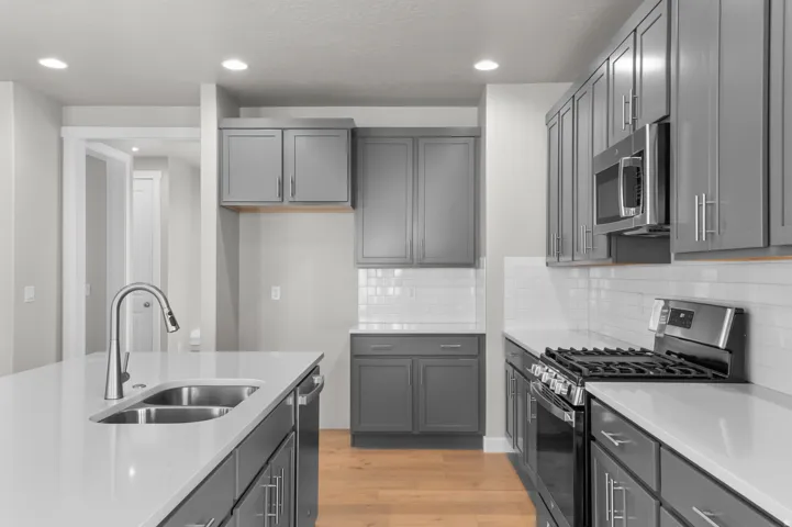 Kitchen featuring gray cabinetry, white countertops, stainless steel appliances, white subway tile backsplash, and wood-finish flooring