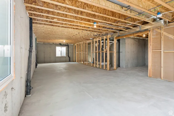 Unfinished lower level featuring exposed wood ceiling joists and concrete flooring