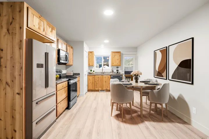 Kitchen and dining area featuring light wood-finish flooring, recessed lighting, wood cabinetry, and stainless steel appliances