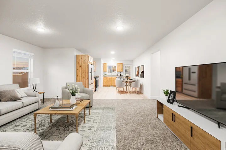 Recessed lighting illuminates the open layout, featuring light wood-finish cabinetry, a window with horizontal blinds, and neutral wall paint