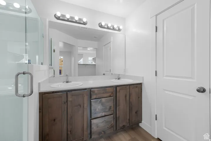 Dual sink vanity with wood-finish cabinetry, light-toned countertop, and modern light fixtures