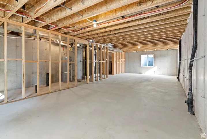 Unfinished basement featuring concrete walls, exposed ceiling joists, and a concrete floor