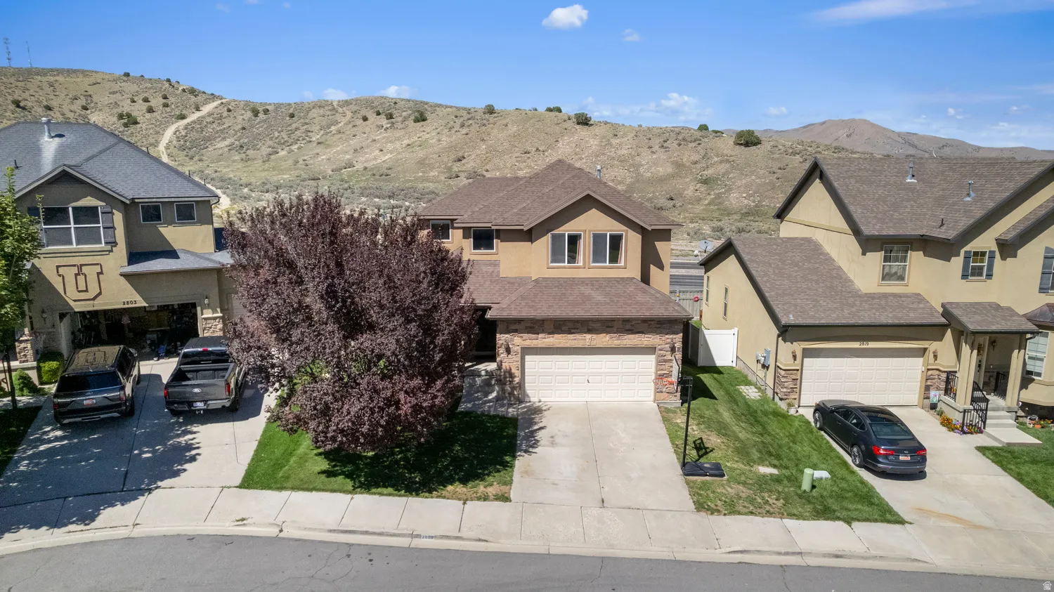 Two-story stucco and stone exterior featuring a two-car garage and concrete driveway