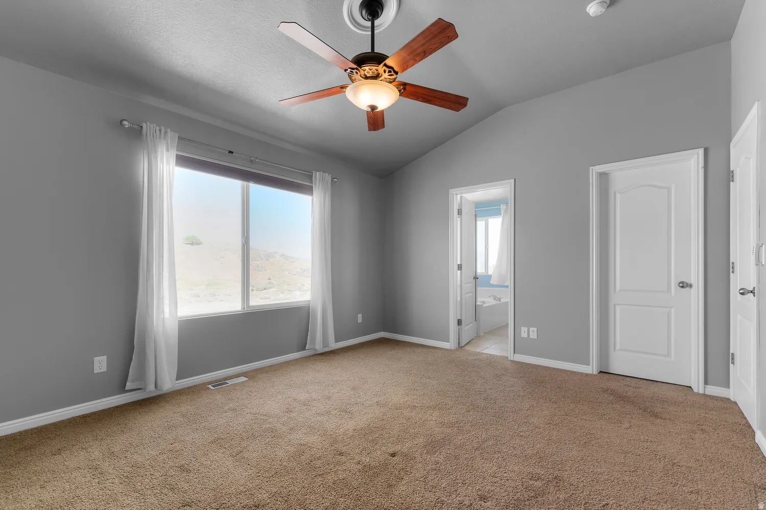 Primary Bedroom-Vaulted ceiling with an attached ceiling fan, expansive window, and broadloom carpeting