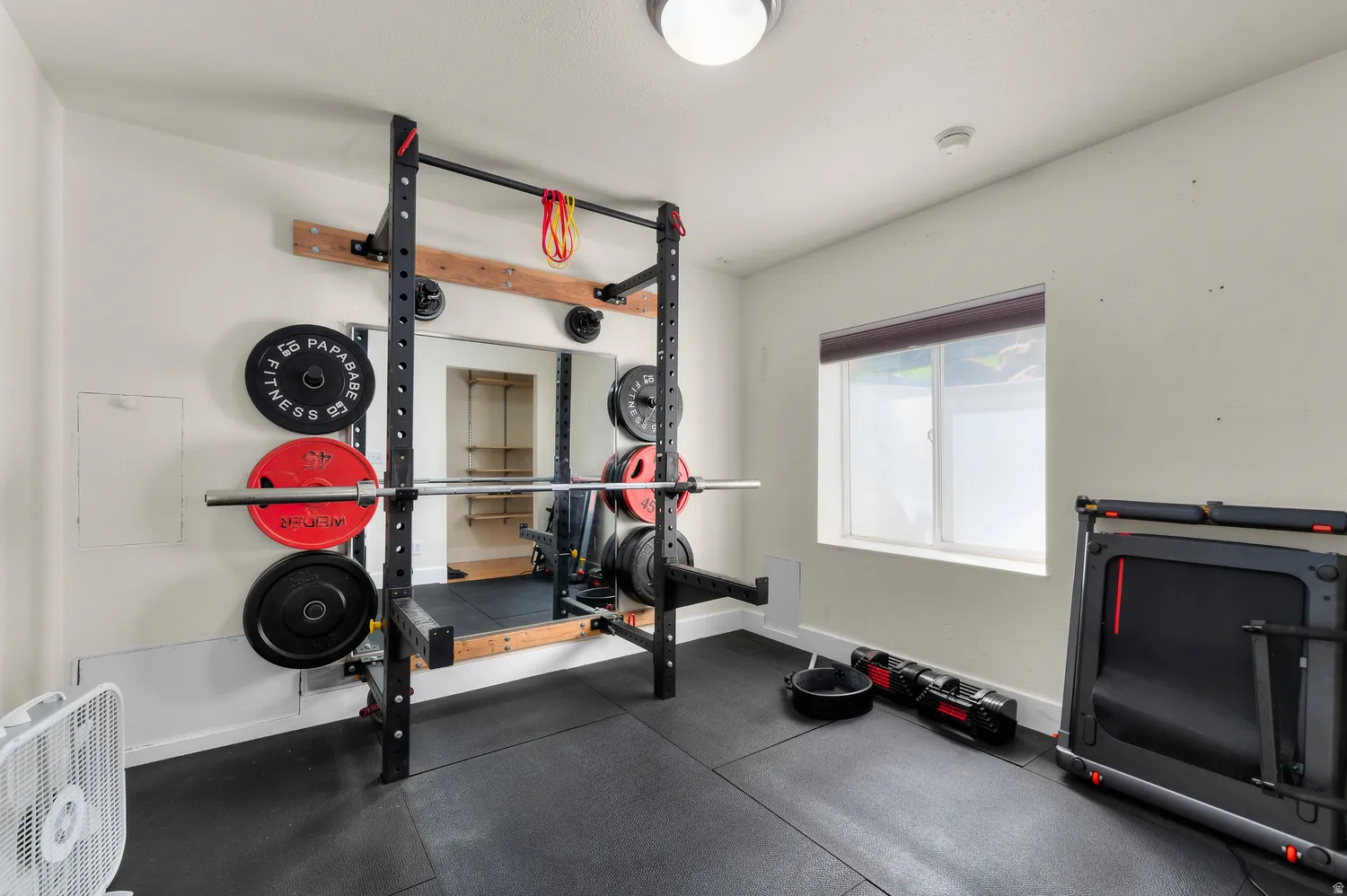 Dedicated room featuring resilient rubber flooring, a built-in mirror, and a window for natural light