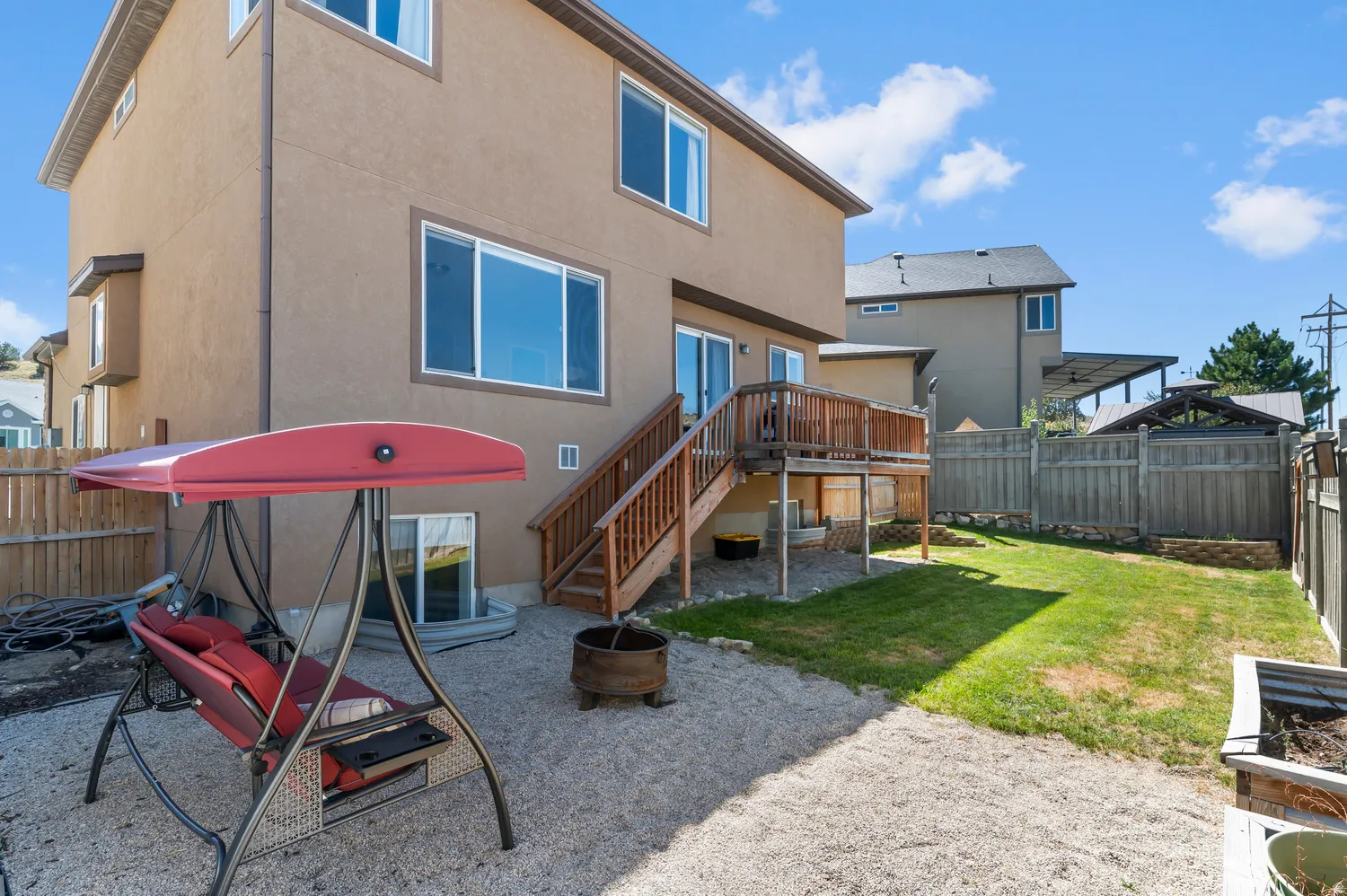 Rear exterior with stucco siding, a wood-finish deck, and a fenced yard featuring both gravel and a grass area
