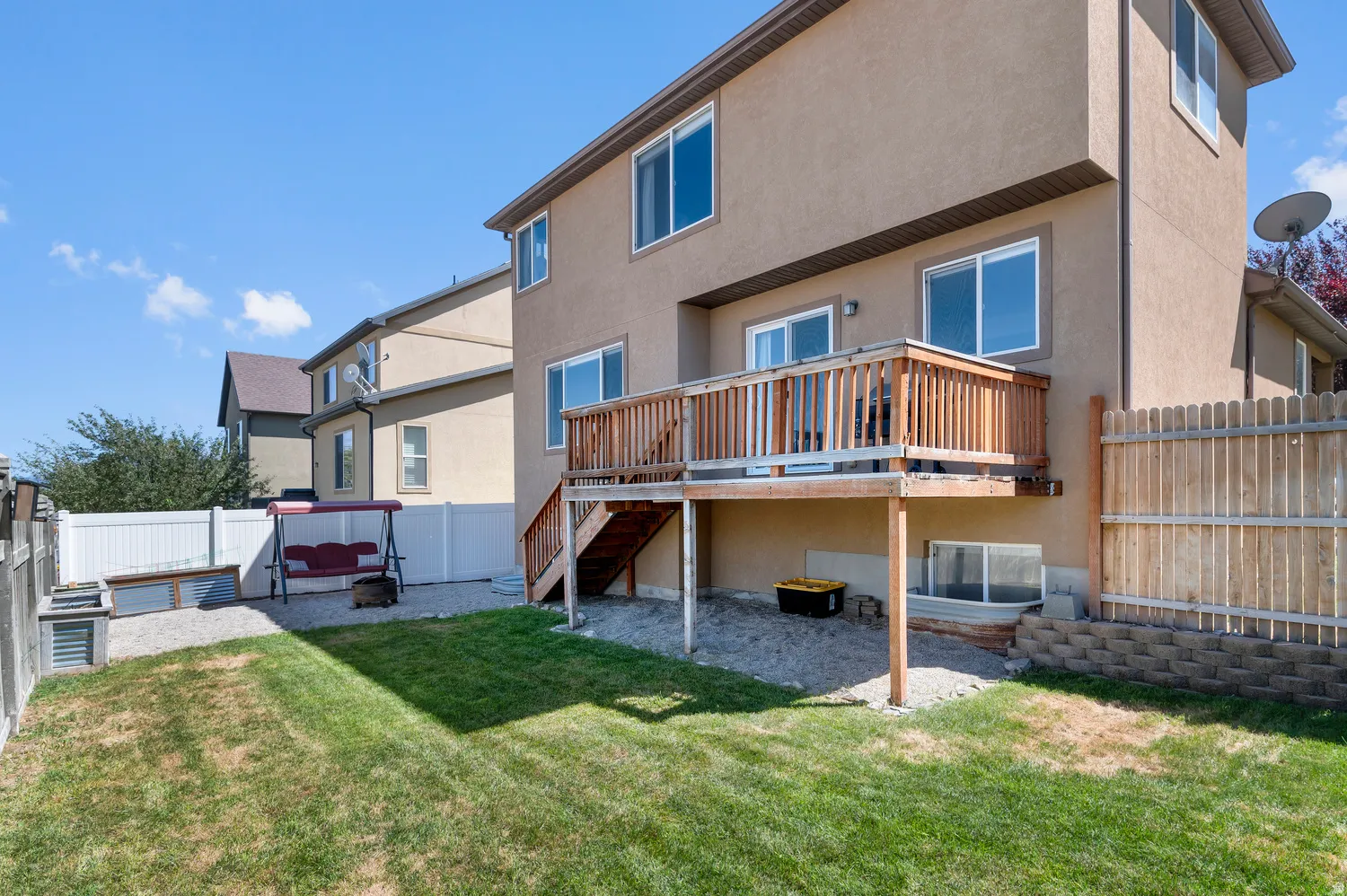 Upper-level wood deck with stairs, leading to a gravel patio area