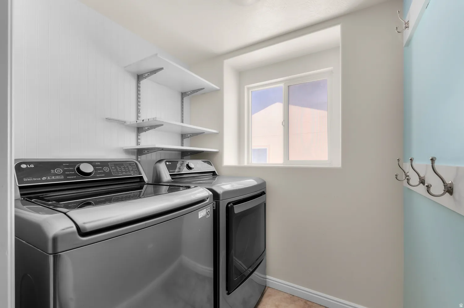 Laundry area featuring a window, built-in shelving, and wall-mounted coat hooks