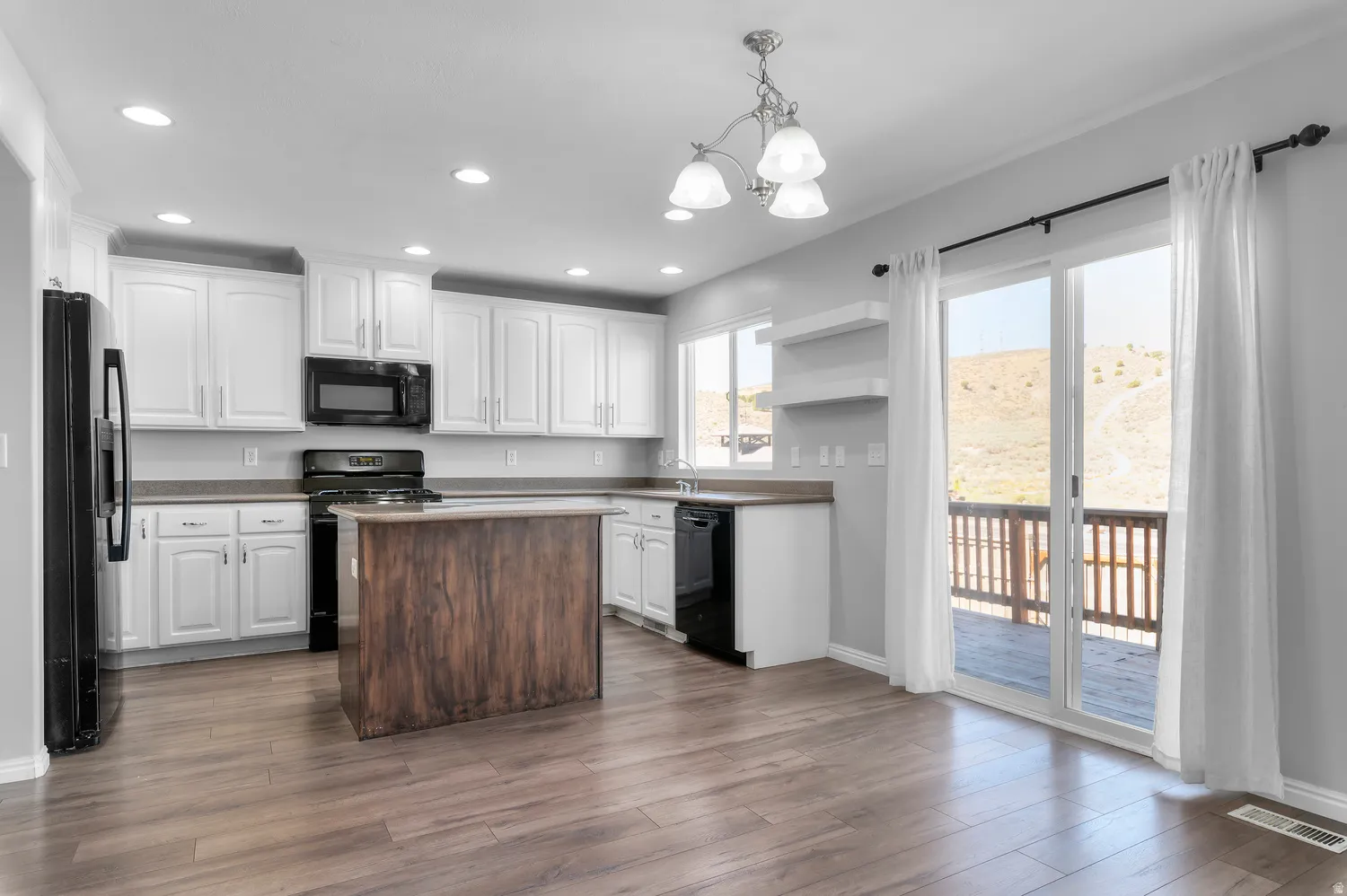 Kitchen featuring white cabinetry, dark wood-finish flooring, a wood-finish island, and black appliances