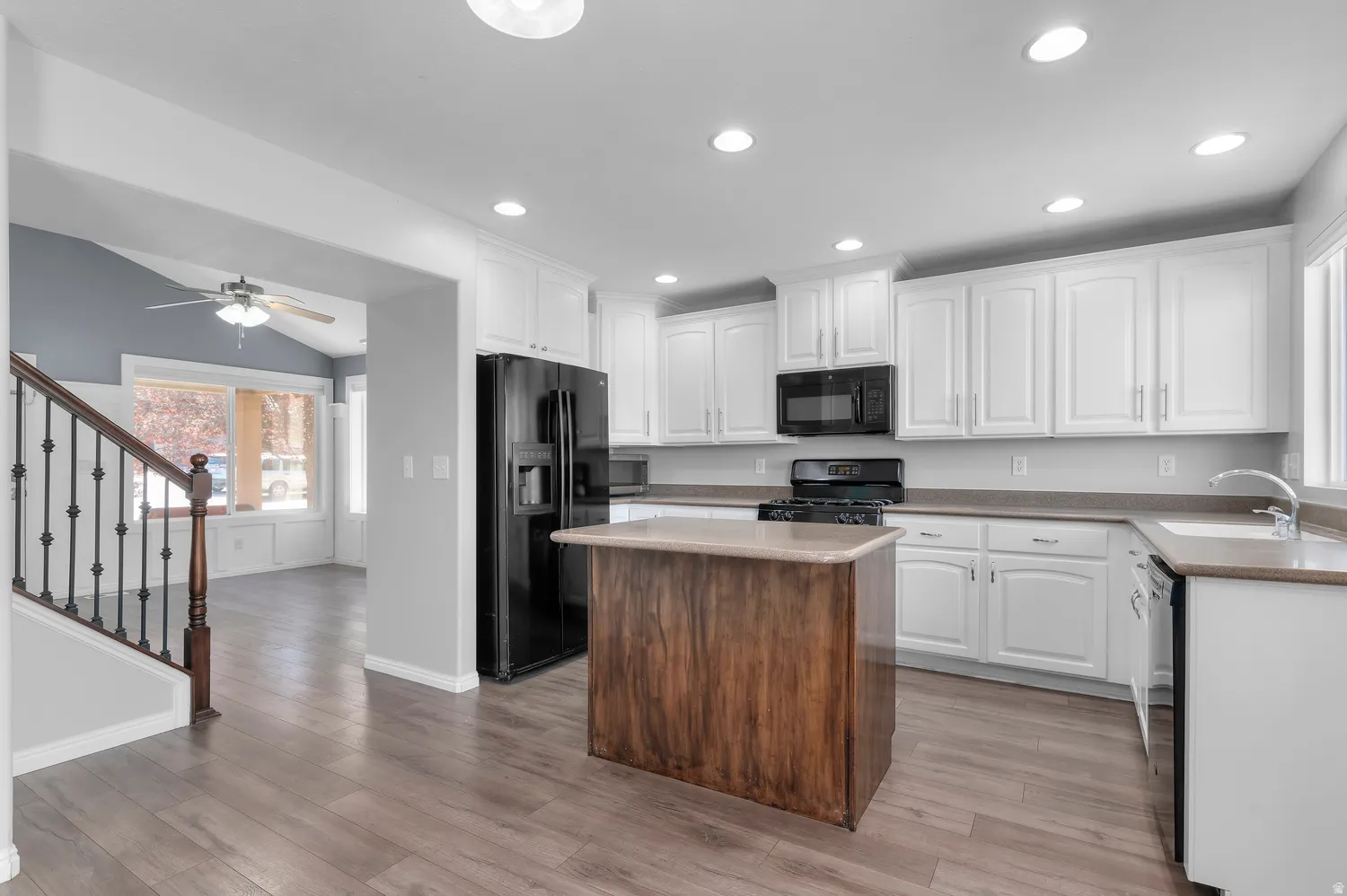 Kitchen featuring white cabinetry, a wood-finish island, black appliances, recessed lighting, and wood-finish flooring