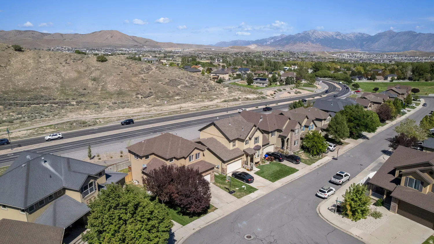 Residential neighborhood with tree-lined streets, surrounded by expansive natural landscapes and distant mountains