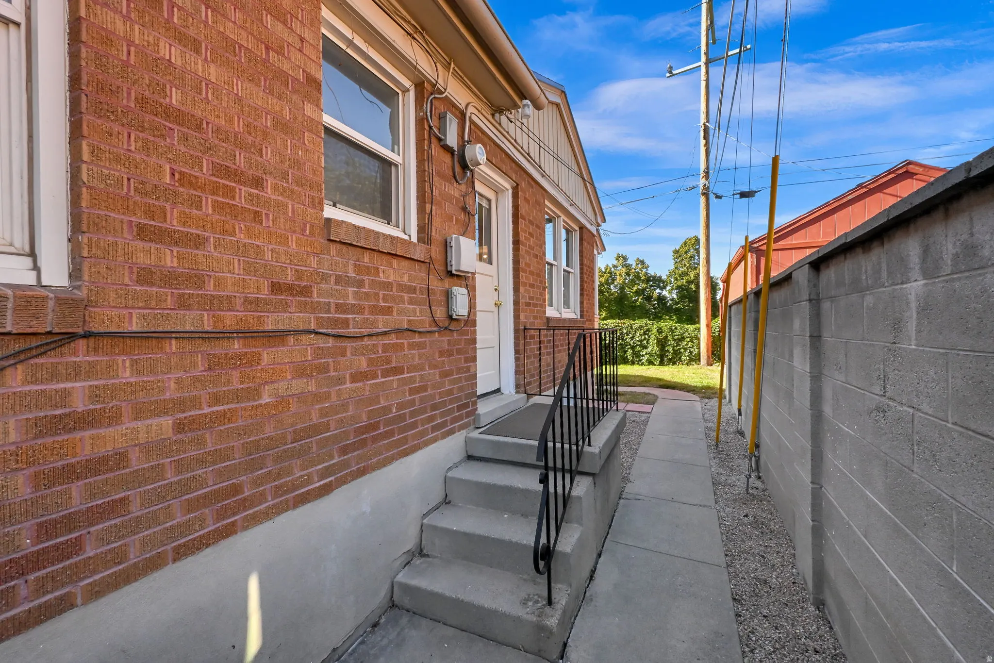 Red brick exterior with white window trim and a concrete block privacy wall