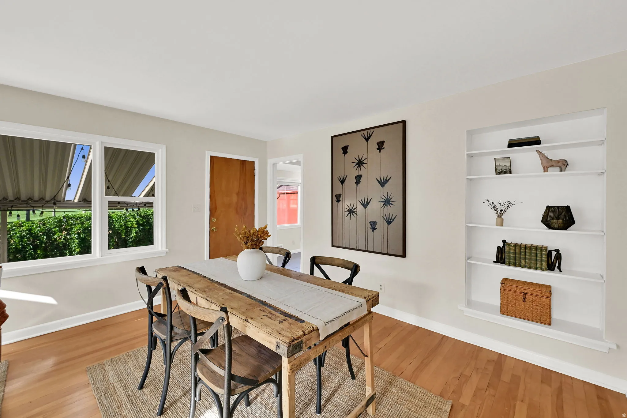 Wood-finish flooring, white trim, recessed built-in shelving, and a solid wood interior door