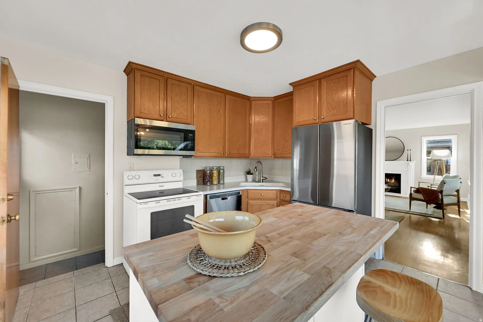 Kitchen featuring wood cabinetry, stainless steel appliances, a wood-finish island countertop, and tile flooring