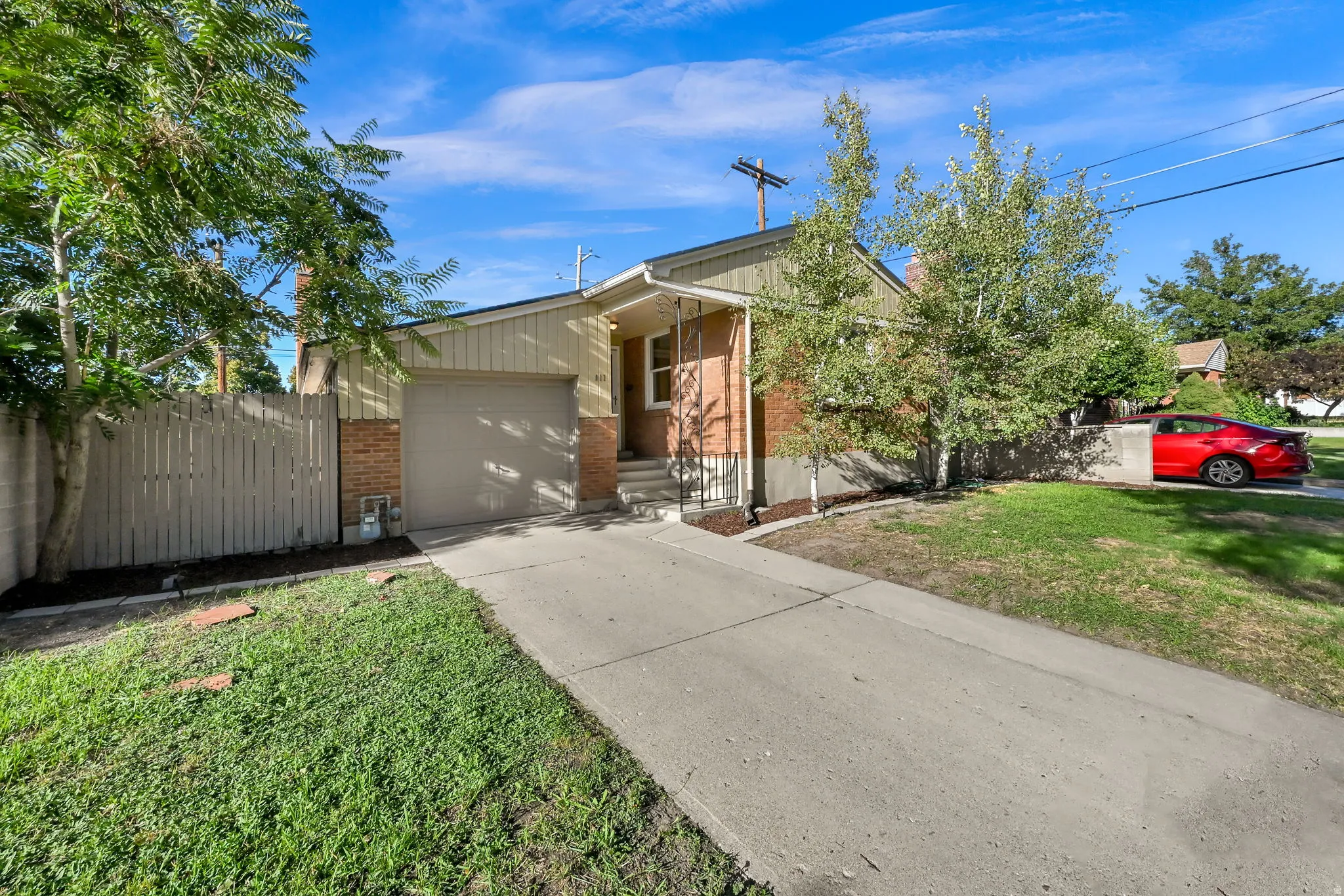 Brick and siding exterior with an attached garage, concrete driveway, and mature landscaping
