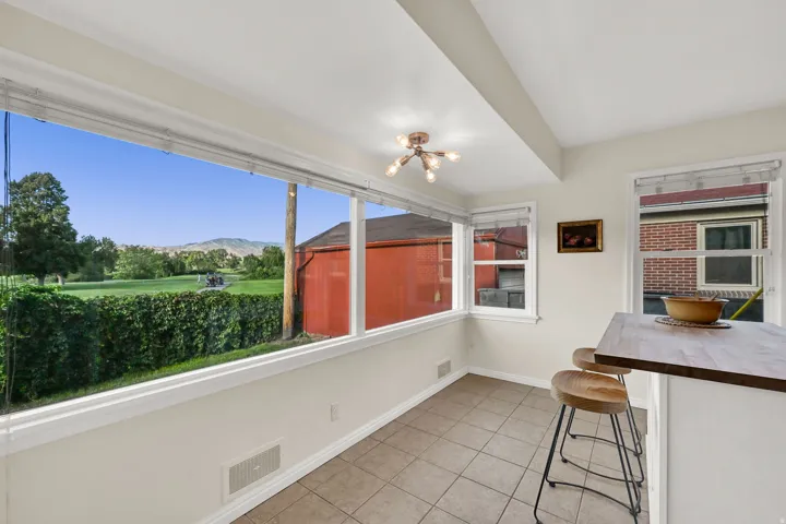 Expansive window wall with a golf course backdrop, tile flooring, built-in breakfast bar, and contemporary ceiling light fixture