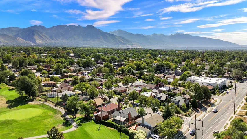 Expansive neighborhood with mature trees, green spaces, and mountain backdrop