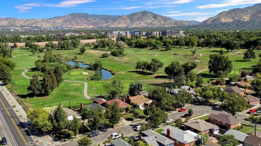 Expansive green landscape with mature trees and a tranquil pond, featuring distant mountains