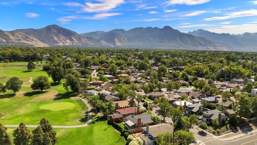 Expansive surrounding landscape featuring a golf course, mature trees, and mountainous terrain