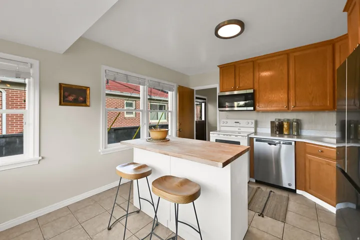 Kitchen with wood-finish cabinetry, stainless steel dishwasher, and a center island with a wood countertop