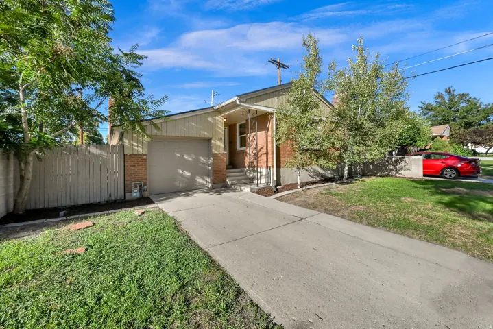 Brick and siding exterior with an attached garage, concrete driveway, and mature landscaping