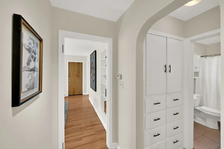 Hardwood flooring, arched doorway, built-in storage cabinetry, built-in shelving, and a wood-panel entry door