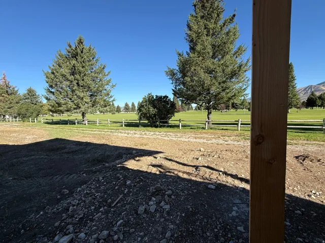 Expansive green landscape with mature evergreen trees and a mountain backdrop