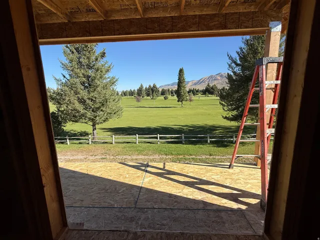 Expansive outdoor space featuring a manicured lawn, distant mountains, and a perimeter fence
