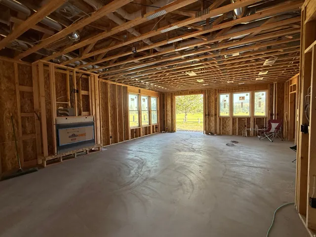 Open-concept floor plan with exposed wood framing, multiple window openings, and a built-in fireplace structure