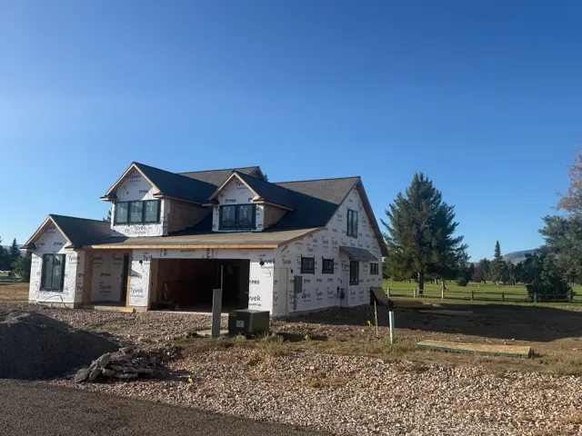 Two-story residence under construction featuring multiple gables, an attached garage, and a dark shingle roof