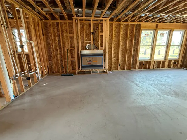 Unfinished interior framing with multiple windows, an installed fireplace, and a concrete slab foundation