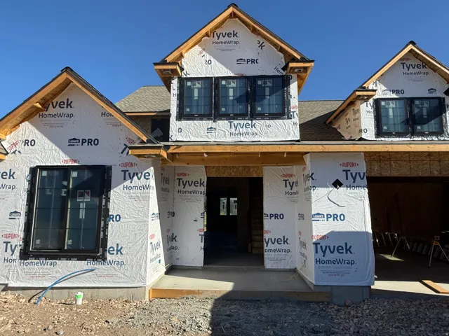 New construction framing with multiple gable rooflines and black-framed windows