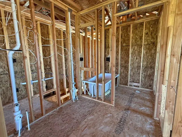 New construction framing showcasing plumbing and electrical rough-ins, with a built-in tub