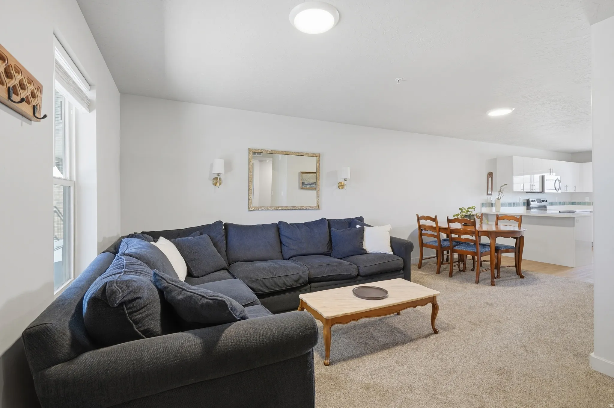 Open-concept living area featuring recessed lighting, a carpeted floor, and a bright window
