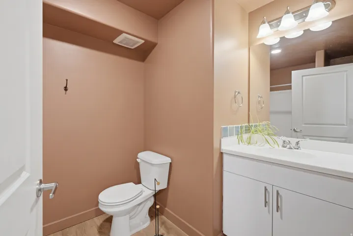 Bathroom featuring a white vanity with integrated sink, chrome faucet, white flat-panel cabinetry, and wall-mounted light fixture